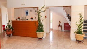 A reception area with a wooden desk, potted plants, and a staircase.