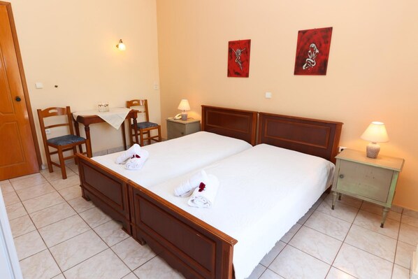 Habitación de hotel con cama doble, dos mesitas de noche, una silla, una mesita pequeña y dos lámparas de pared.