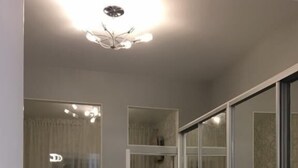 A modern room with a large sliding glass door, a ceiling light fixture, and a small cabinet.