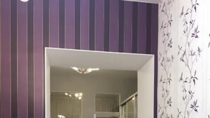 A room with a purple striped wall, a white chair, and a light blue table.