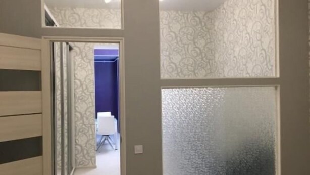 A bedroom with a bed, a wardrobe, and a door leading to another room.