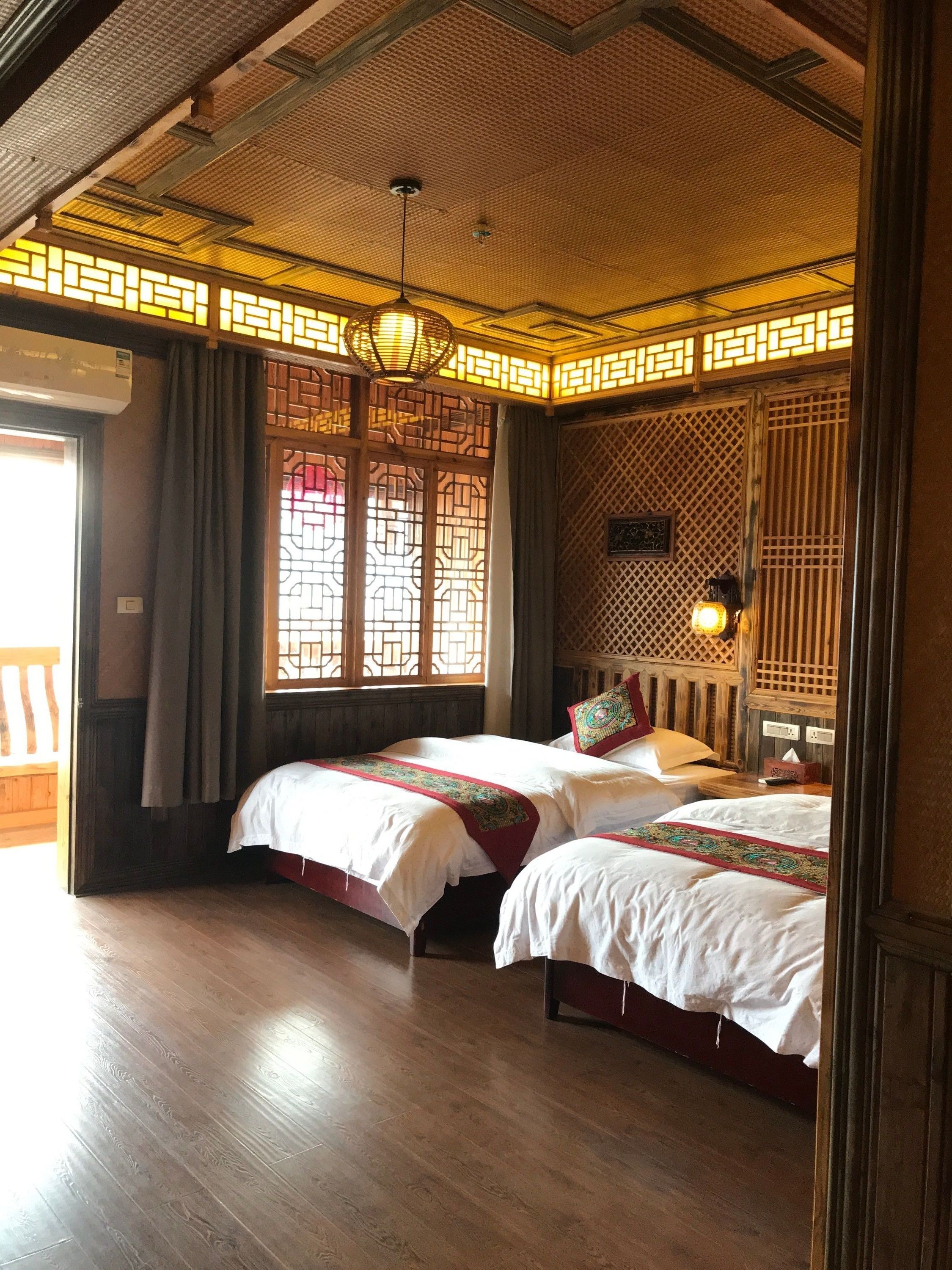 A traditional room with two beds, wooden flooring, and a decorative ceiling.