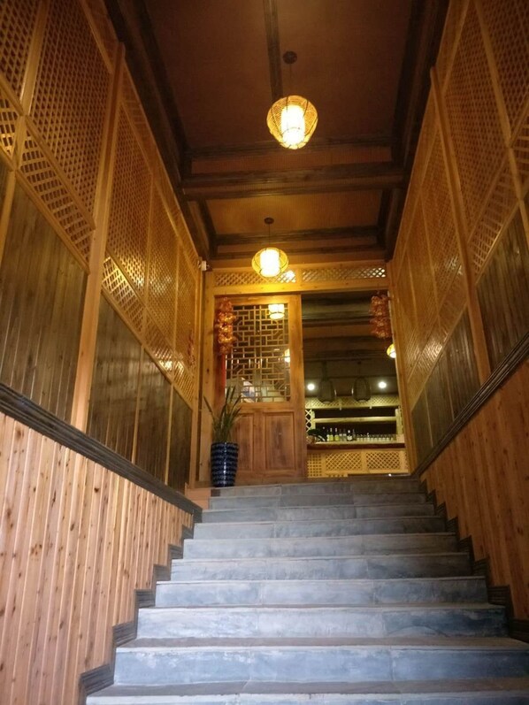 A wooden staircase leading to a room with a traditional design, including lattice panels and a hanging light fixture.