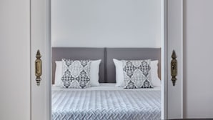 A bedroom with a bed, patterned pillows, and a white headboard.