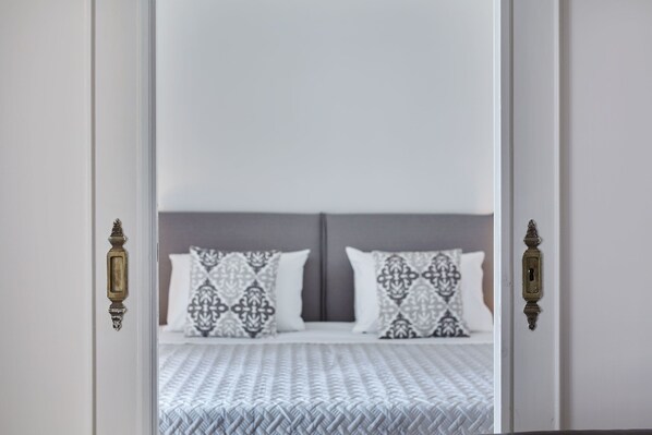 A bedroom with a bed, patterned pillows, and a white headboard.