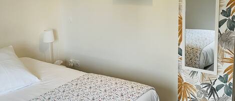 Un dormitorio con cama, un cuadro, una lámpara y un espejo.