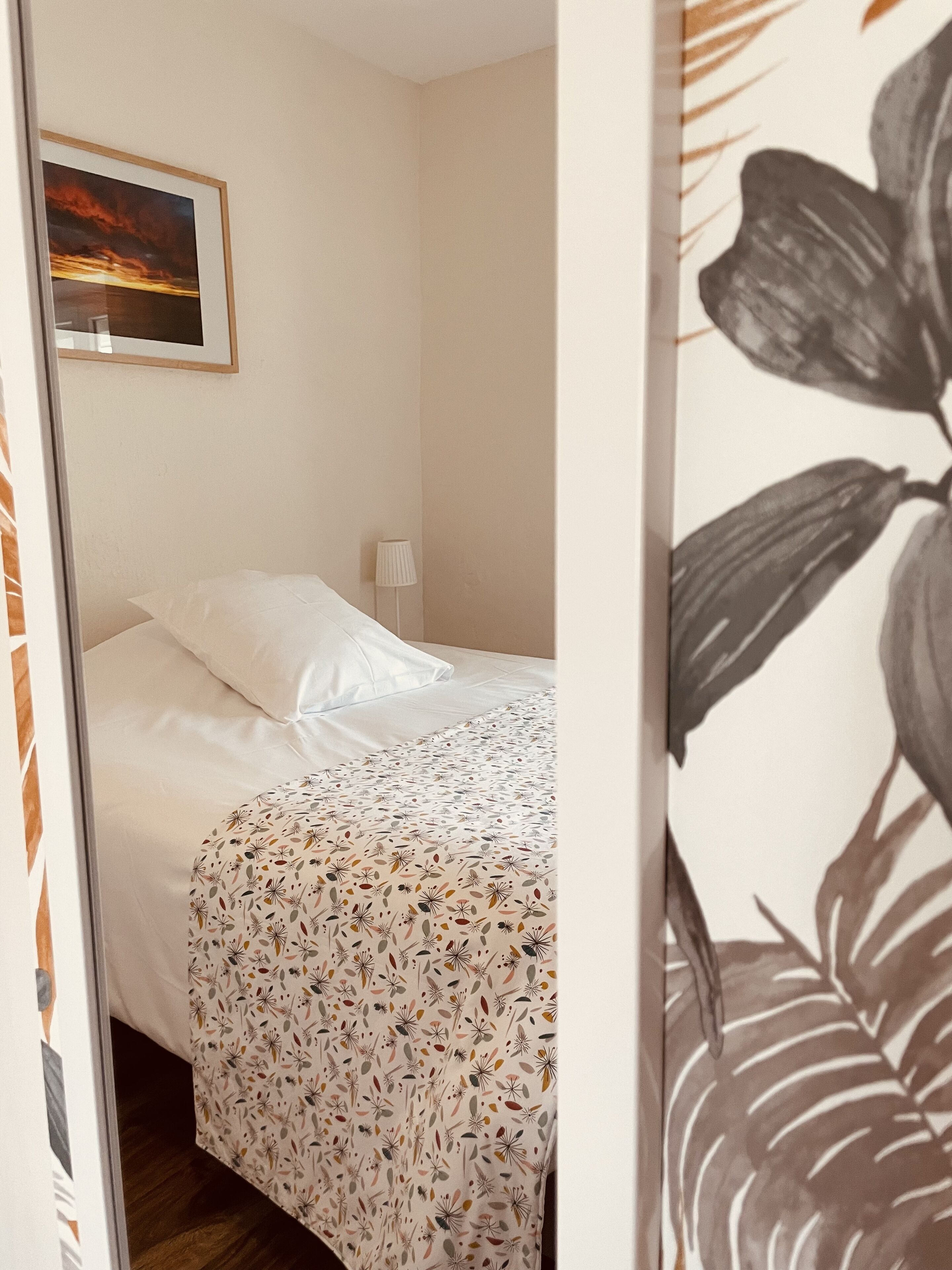 Une chambre à coucher avec un lit, une table de chevet, une lampe et un tableau encadré au mur.