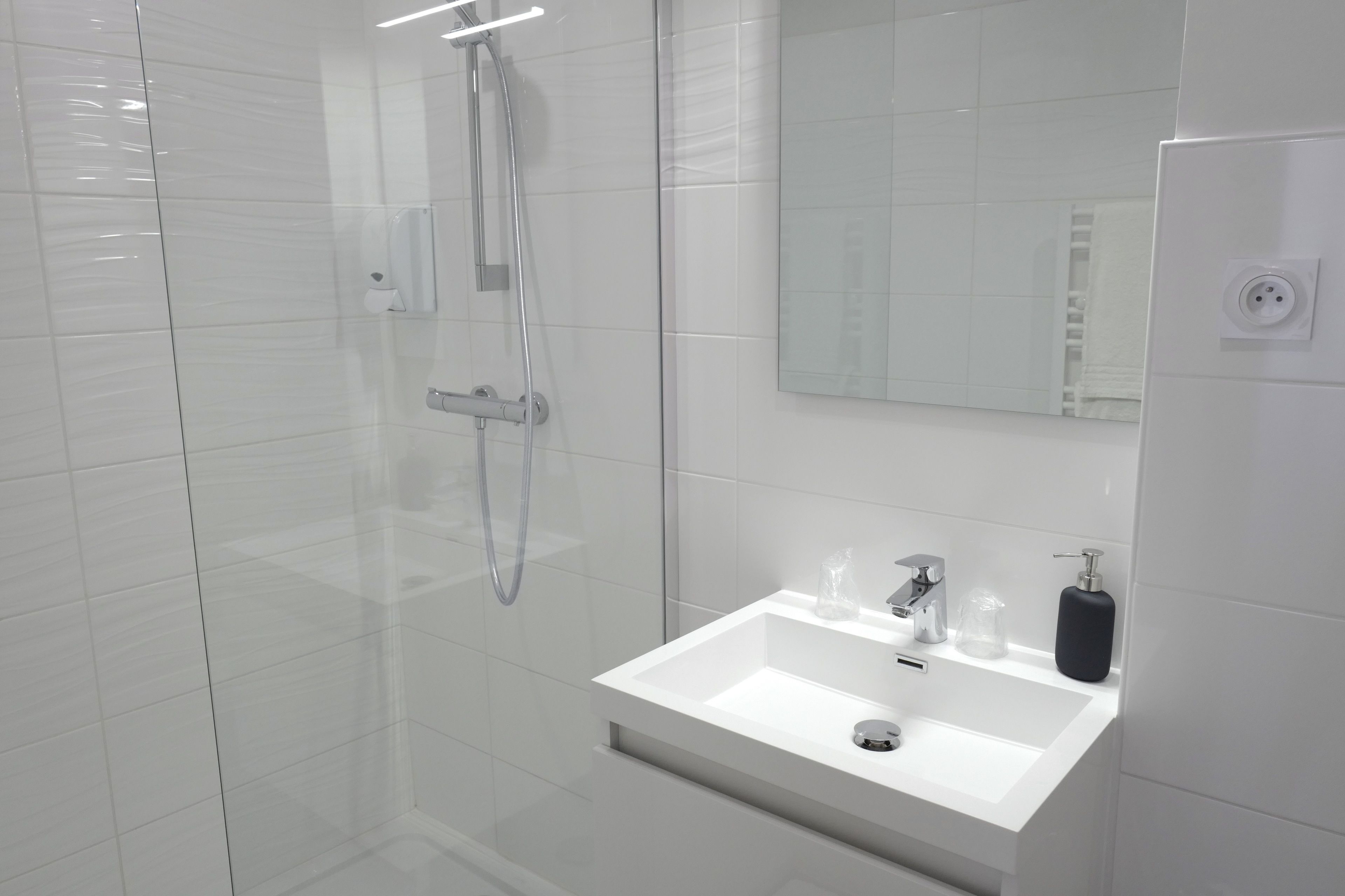 A modern bathroom with a glass-enclosed shower, a white sink, and a mirror above it.