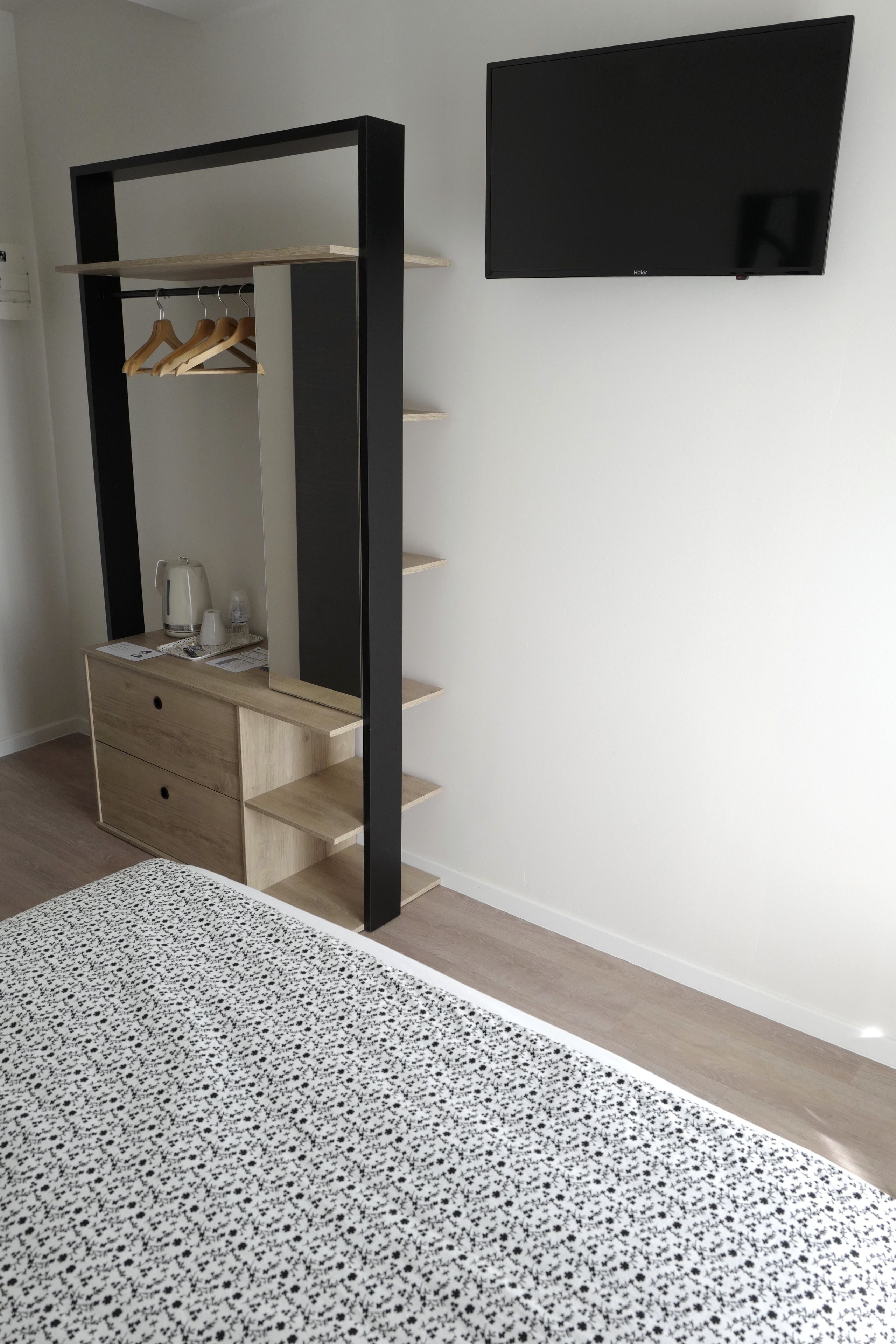 Un dormitorio con un aparador de madera, un espejo y un televisor negro montado en la pared.