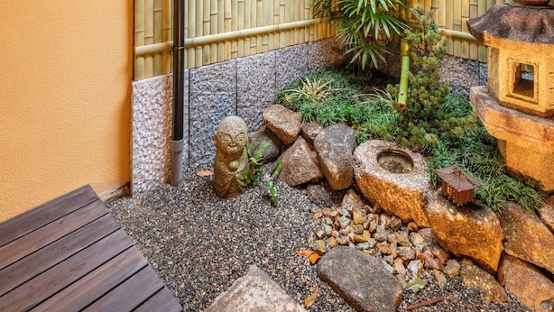 A traditional Japanese garden with bamboo walls, a wooden deck, and a small rock garden. - KumoMachiya Goshohigashi (Kyoto)