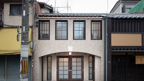 A traditional Japanese building with a tiled roof, a wooden front door, and multiple windows. - KumoMachiya Goshohigashi (Kyoto)