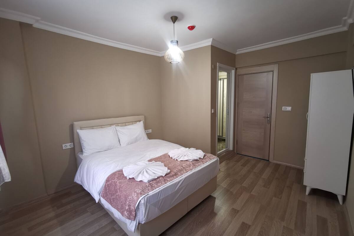 A bedroom with a bed, a wardrobe, a ceiling light, and a door.