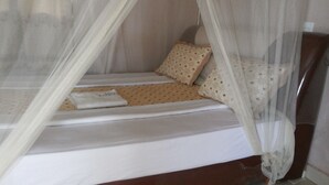 A bed with a canopy, a pillow, and a folded towel. - Blue Dove Hotel (Koboko)