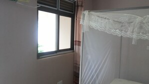 A room with a window, a bed with a white canopy, and a curtain. - Blue Dove Hotel (Koboko)