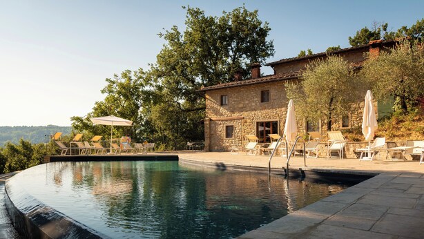 A stone building with a pool, surrounded by trees and outdoor seating. - Fattorie di Celli (Poppi)