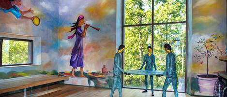 Quarto com mural, uma janela grande e um banco.