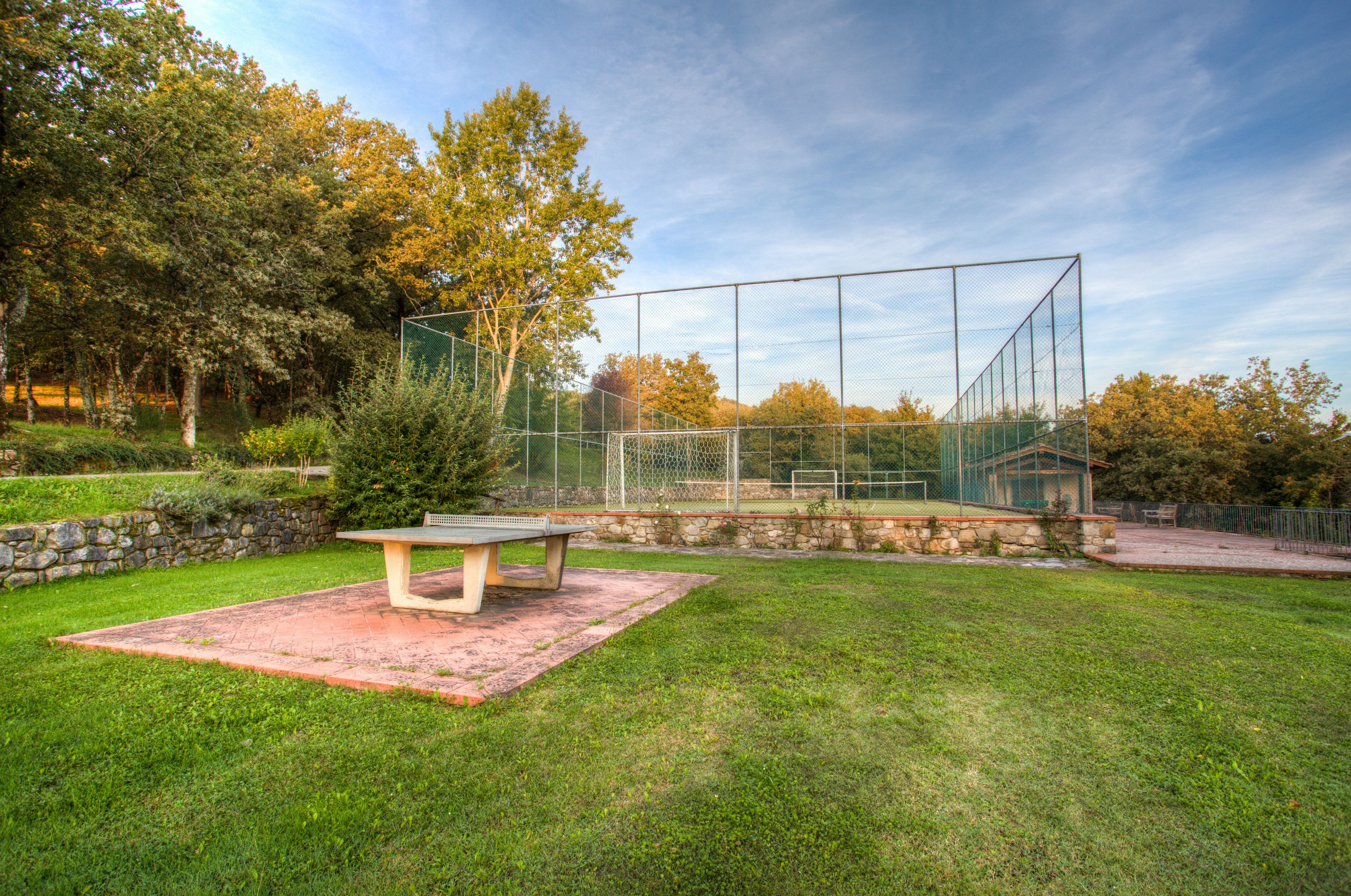 Ein Tennisplatz mit Netz, einer Steinmauer und einer Bank.