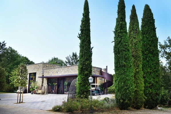 A stone building with a modern design, featuring a large glass door and a spiral staircase. - Fattorie di Celli (Poppi)