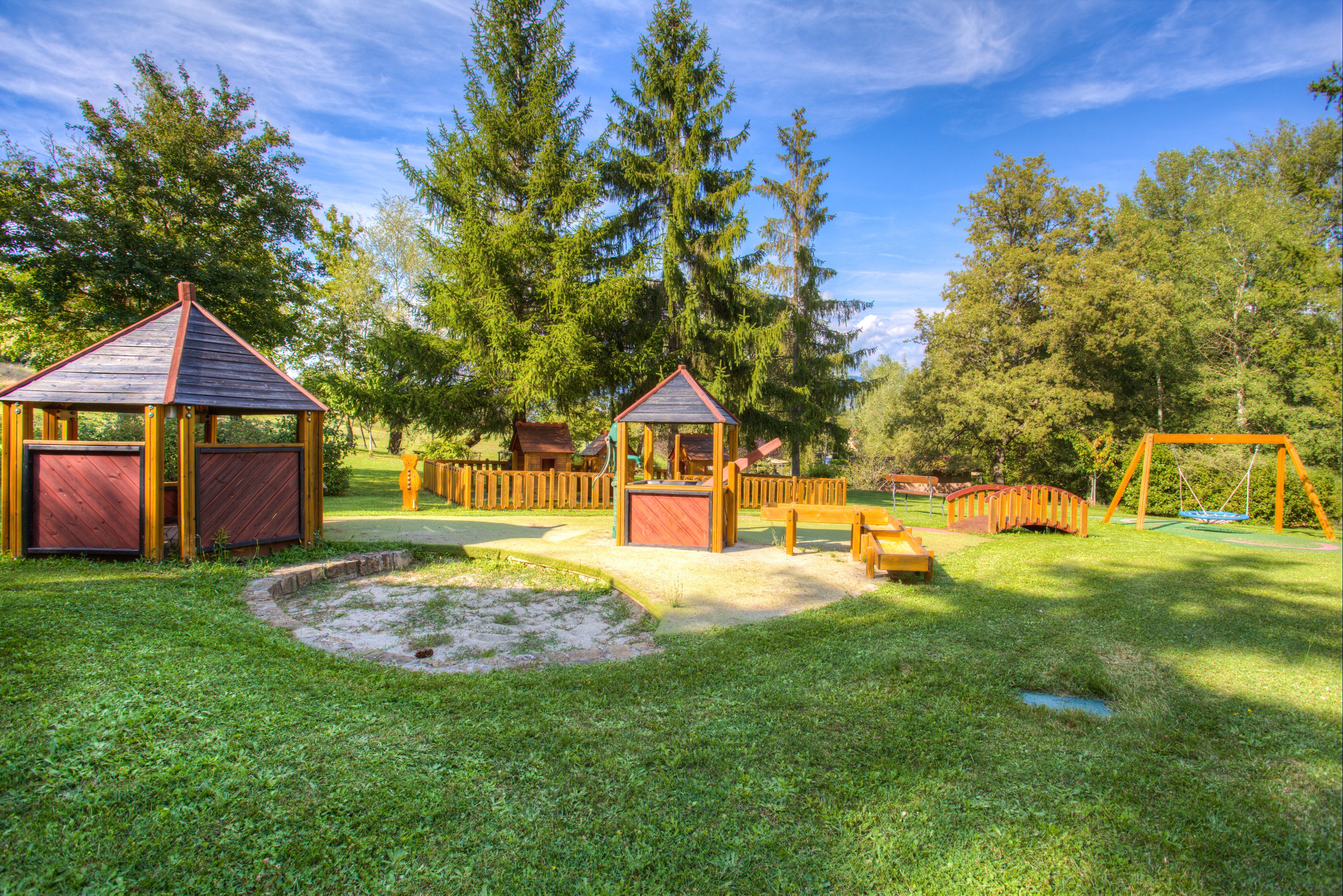 A playground with wooden structures, including a swing set and a small building.