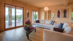 A spacious living room with a large sofa, a coffee table, and a fireplace. There are large windows with a view of the outdoors. - Fattorie di Celli (Poppi)