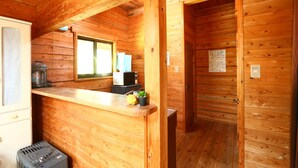 A wooden cabin interior with a kitchenette, a window, and a door. - Kizin (Takamori)