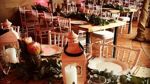 A banquet hall with wooden tables set for a formal event, adorned with white plates, glasses, and decorative lanterns. - OUT OF Nature Country Lodge (Windhoek)