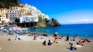 A coastal town with buildings on a hillside overlooking the sea, a sandy beach with people, and a clear blue sky. - B&B Relax in Pompei (Pompei)