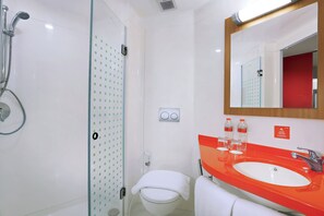A modern bathroom with a glass shower enclosure, a white toilet, and a red sink with a mirror above it. - Starlet Hotel Jakarta Airport (Tangerang)
