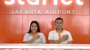 Mostrador de recepción en Starlet Jakarta Airport, con una decoración en rojo y blanco.