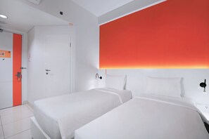 A hotel room with two beds, a white door, and a red accent wall. - Starlet Hotel Jakarta Airport (Tangerang)