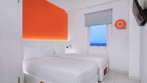 Una habitación de hotel moderna con dos camas, un ventanal con vistas y un televisor de pared.