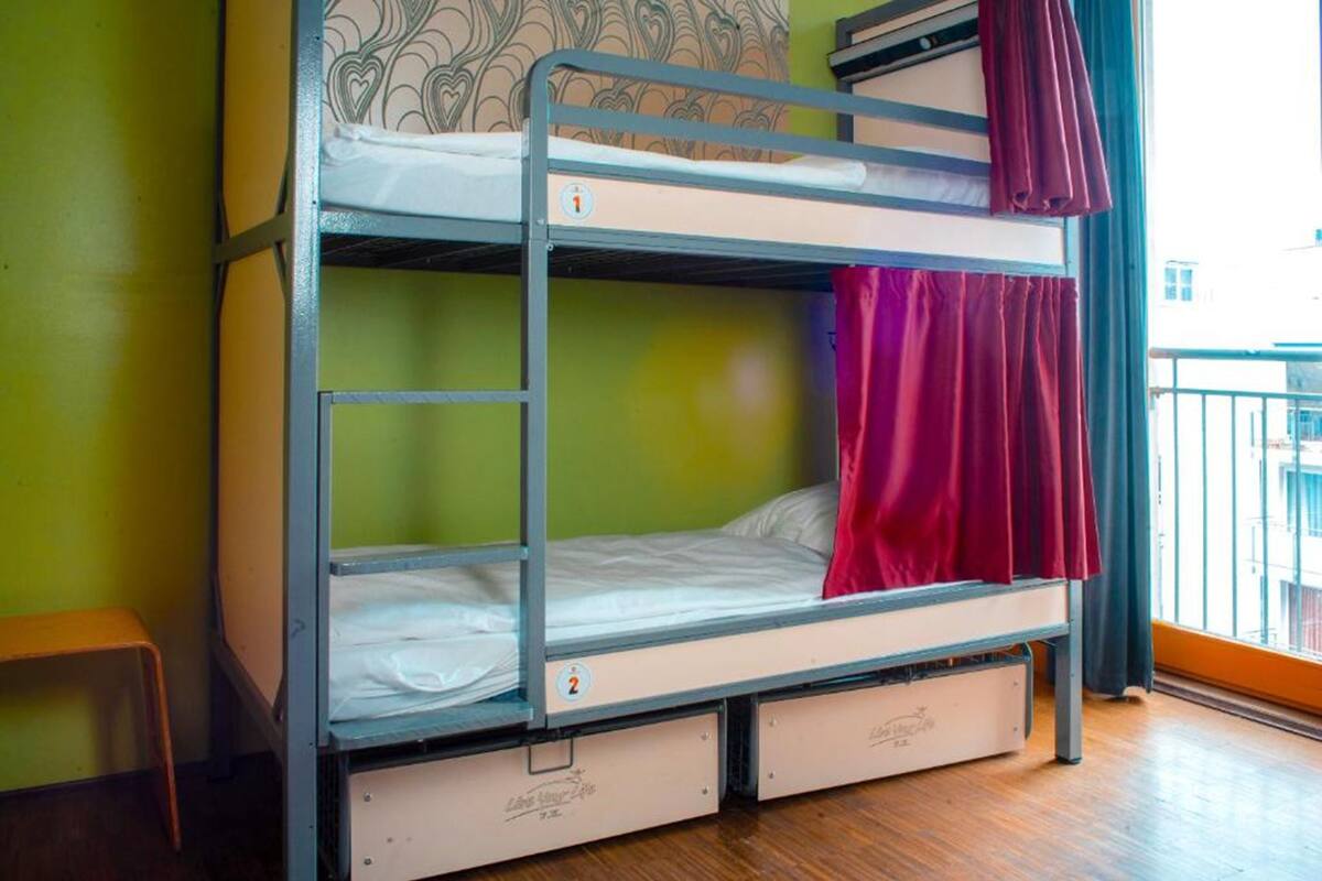 A bunk bed with two levels, each with a mattress and a pillow. There are two drawers under the lower bunk.