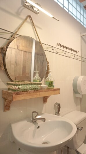 A bathroom with a round mirror, wooden shelf, and a white sink. - Zenstay (Ho Chi Minh City)
