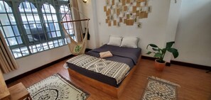 A bedroom with a bed, a hanging chair, a potted plant, and a wall with botanical prints. - Zenstay (Ho Chi Minh City)