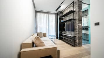 A modern living room with a sofa, a flat-screen TV, and a marble accent wall.