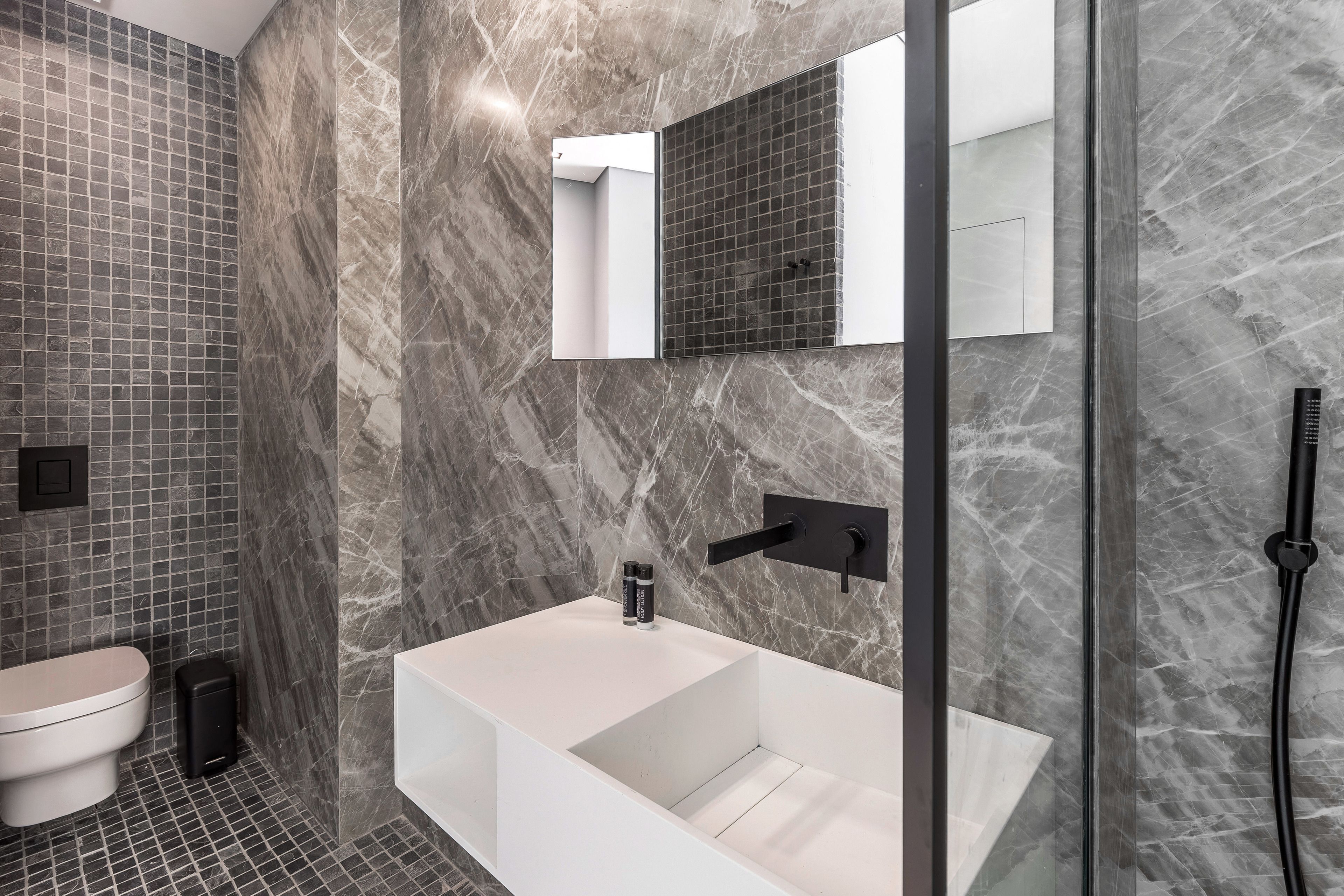 Un baño moderno con una bañera blanca, un inodoro y una zona de ducha.