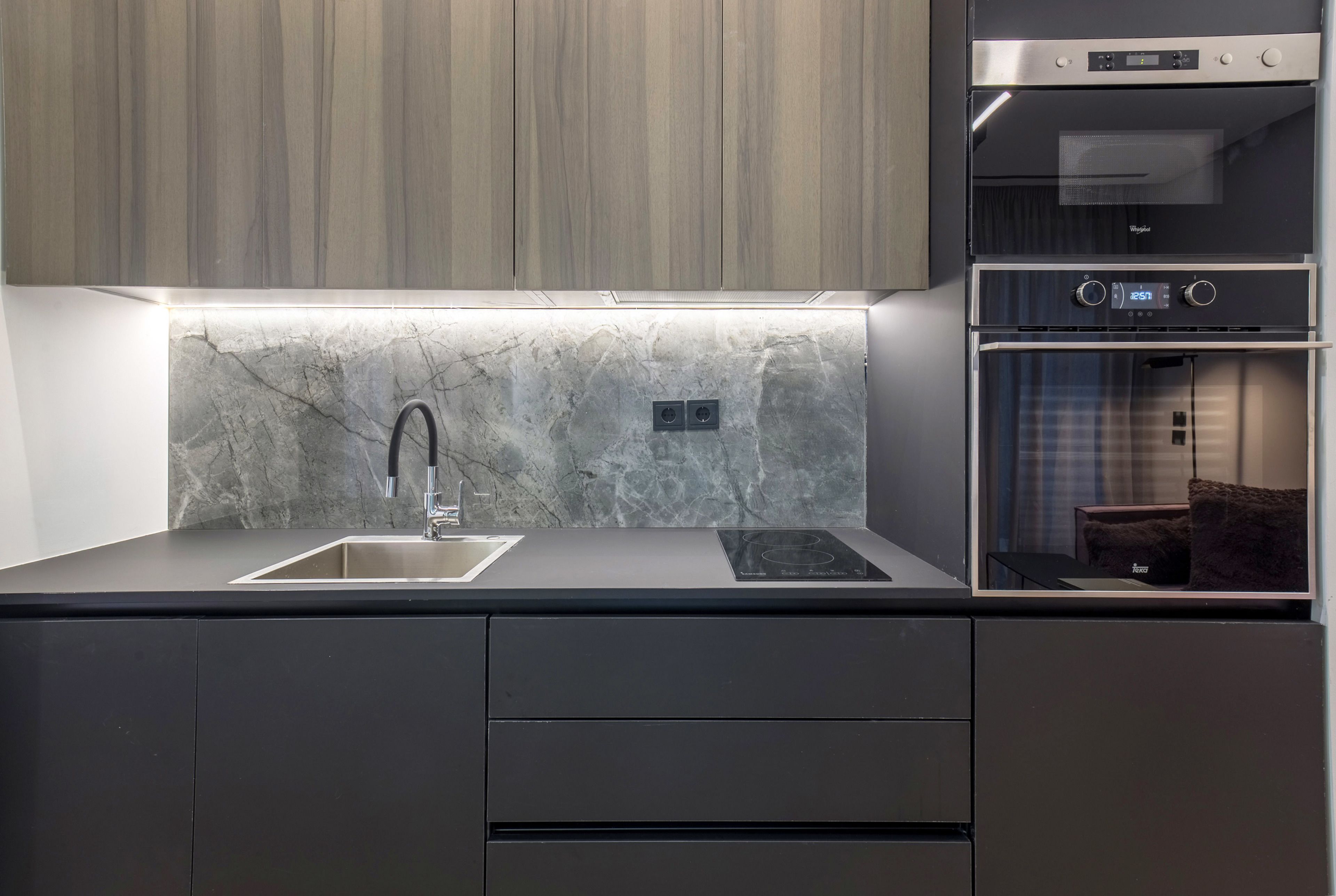 A modern kitchen with a marble backsplash, stainless steel appliances, and a built-in oven.