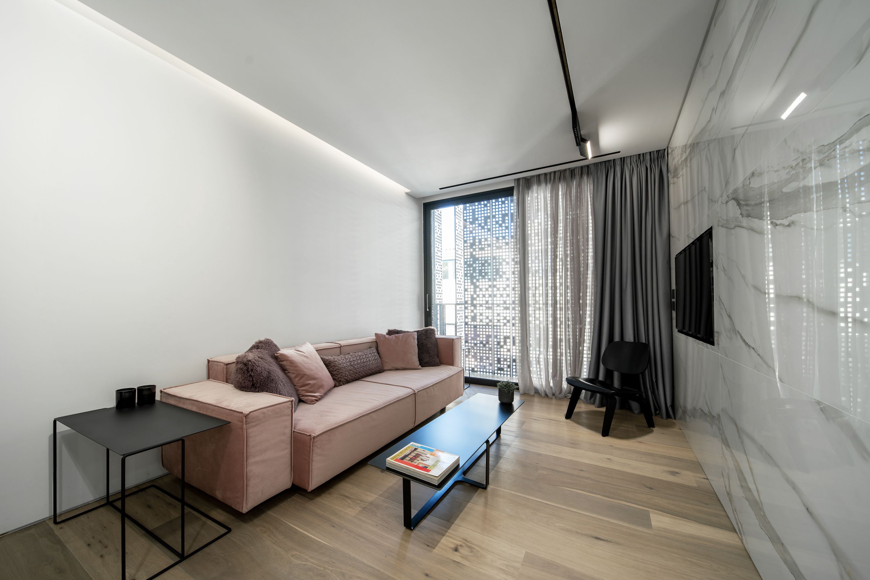 Ein modernes Wohnzimmer mit einer Couch, einem Couchtisch, einem Beistelltisch und einem an der Wand befestigten Fernseher.