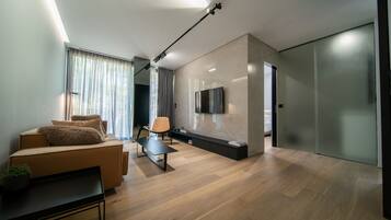 A modern living room with a sofa, a coffee table, and a TV mounted on the wall.