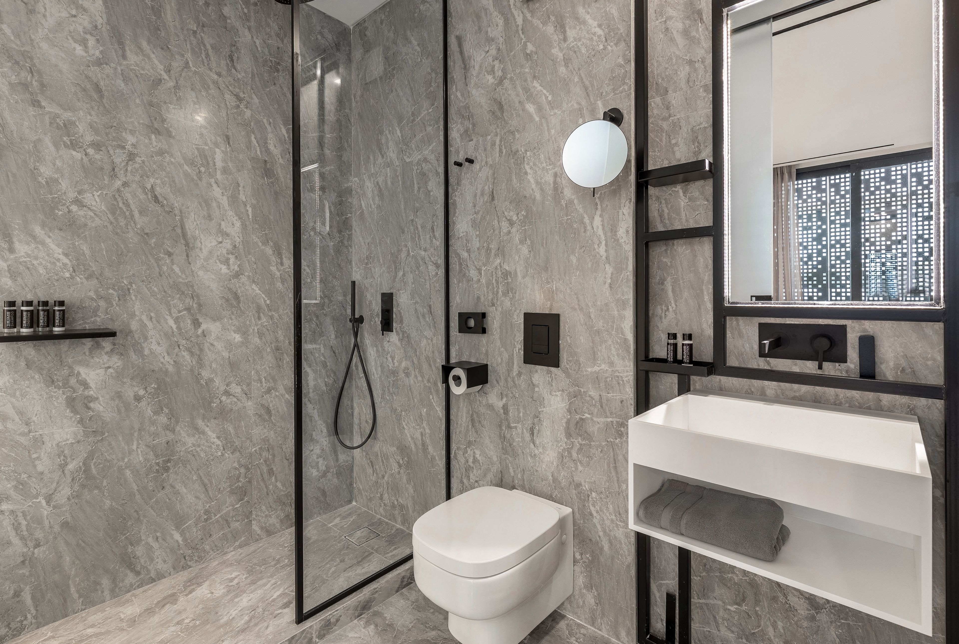 A modern bathroom with a glass-enclosed shower, a white toilet, and a vanity with a mirror.