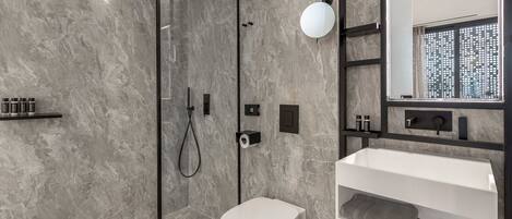 A modern bathroom with a glass-enclosed shower, a white toilet, and a vanity with a mirror.