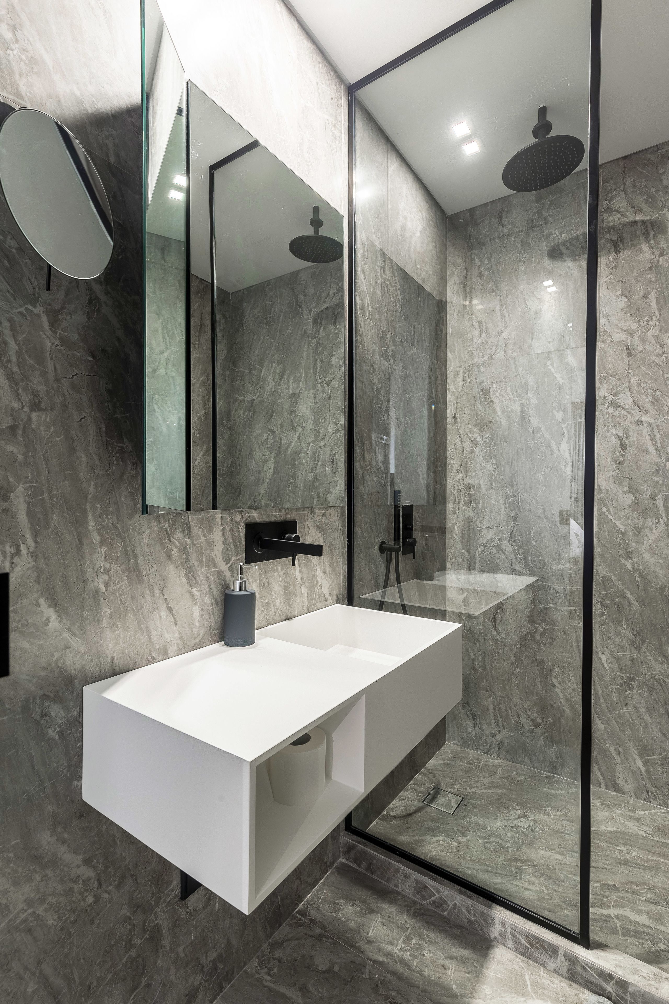 Une salle de bain moderne avec un meuble-lavabo blanc, une douche en verre et un pare-baignoire en marbre.