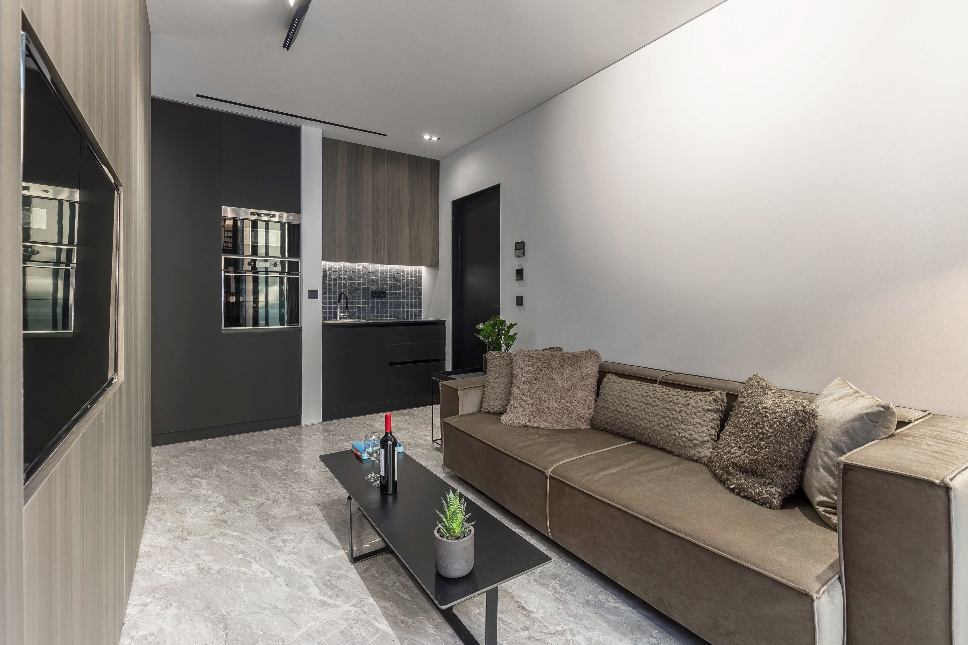 Una sala moderna con sofá, una mesa de centro y una zona de cocina con microondas y armarios.
