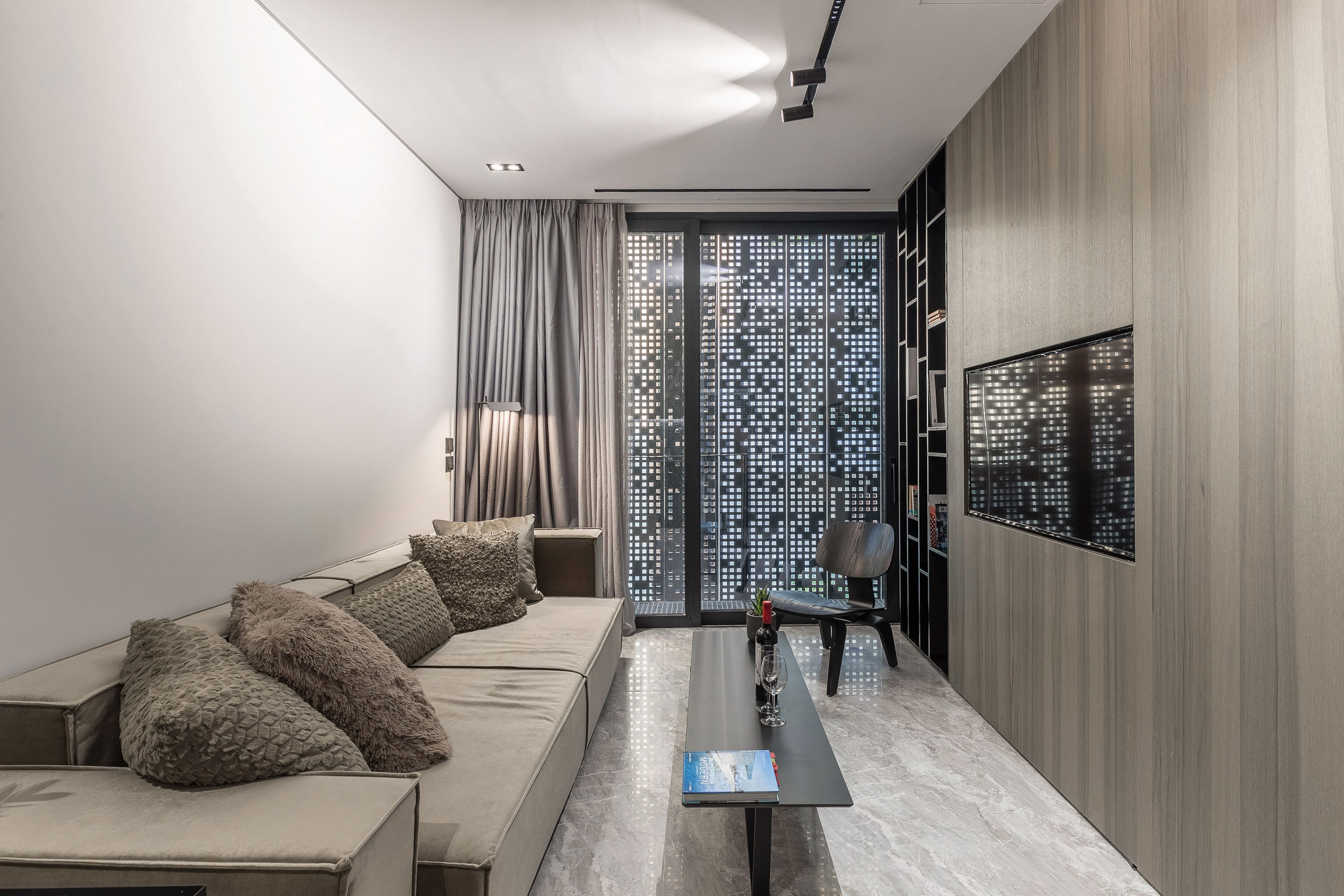 A modern living room with a sofa, a coffee table, and a TV mounted on the wall.