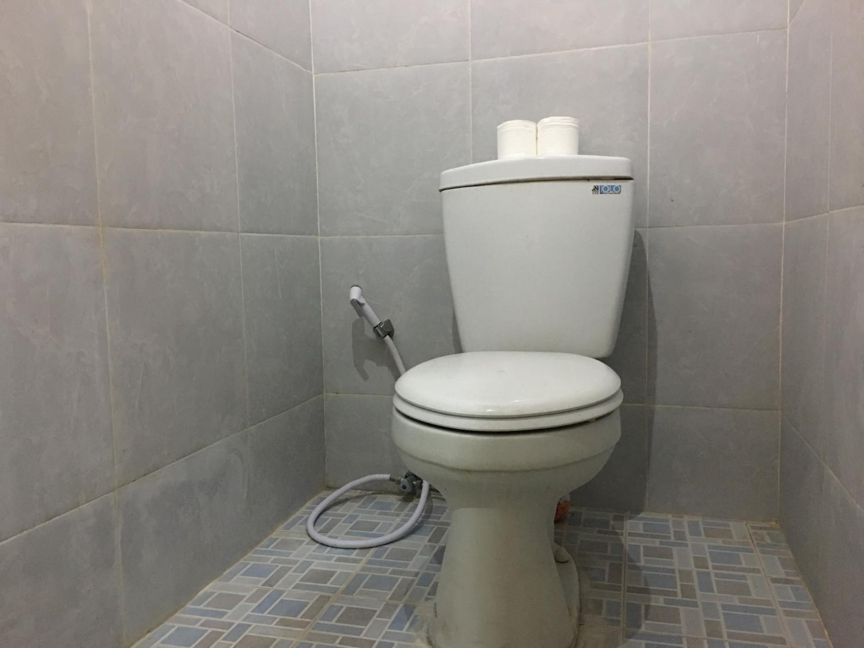 A toilet with a bidet attachment in a tiled bathroom.
