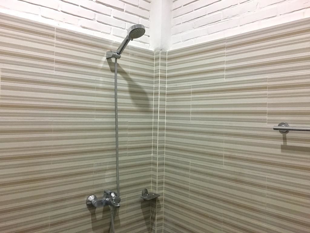 A shower with a handheld showerhead and a wall-mounted faucet.