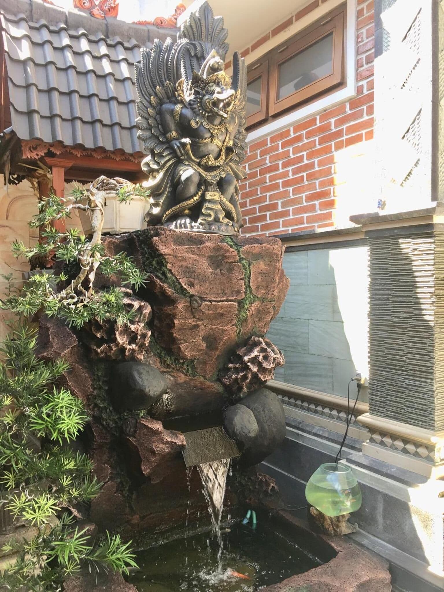 A decorative fountain with a statue on top, surrounded by greenery.