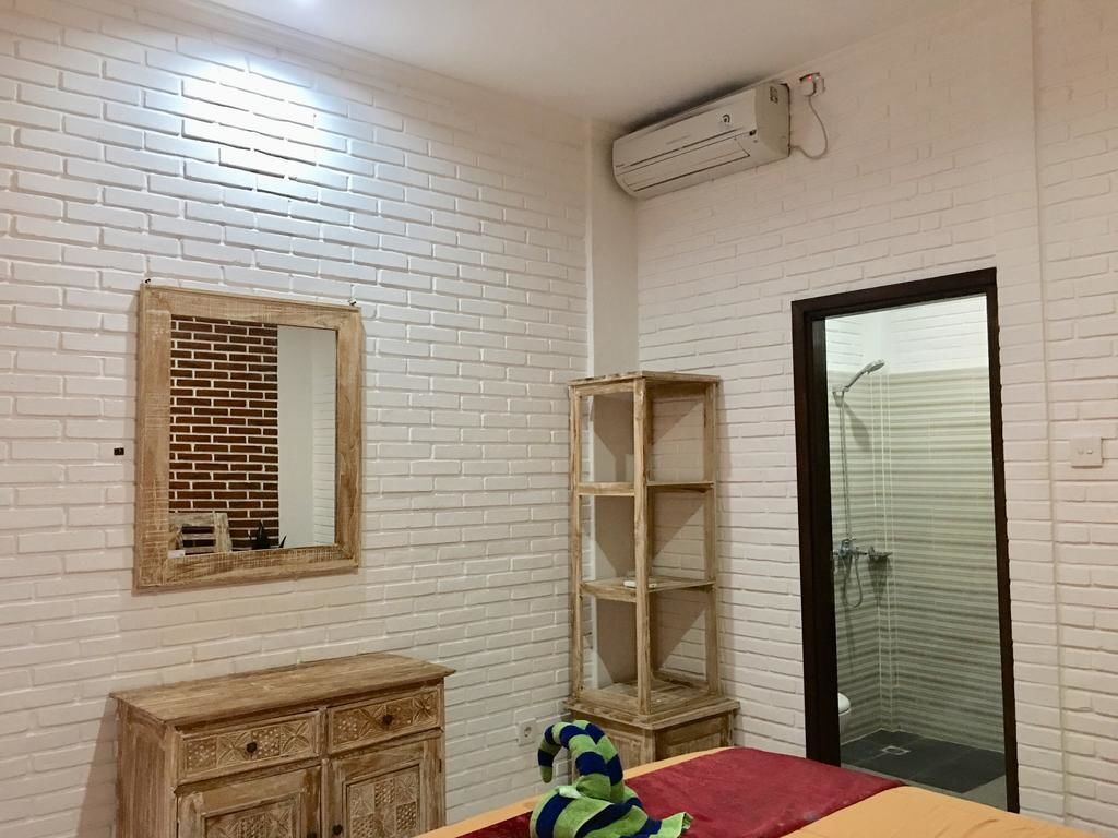 A room with a white brick wall, a wooden dresser, a mirror, a shelf, and a shower area.