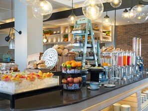Un área de bufé con diferentes opciones de comida, una selección de frutas y una estación de bebidas.