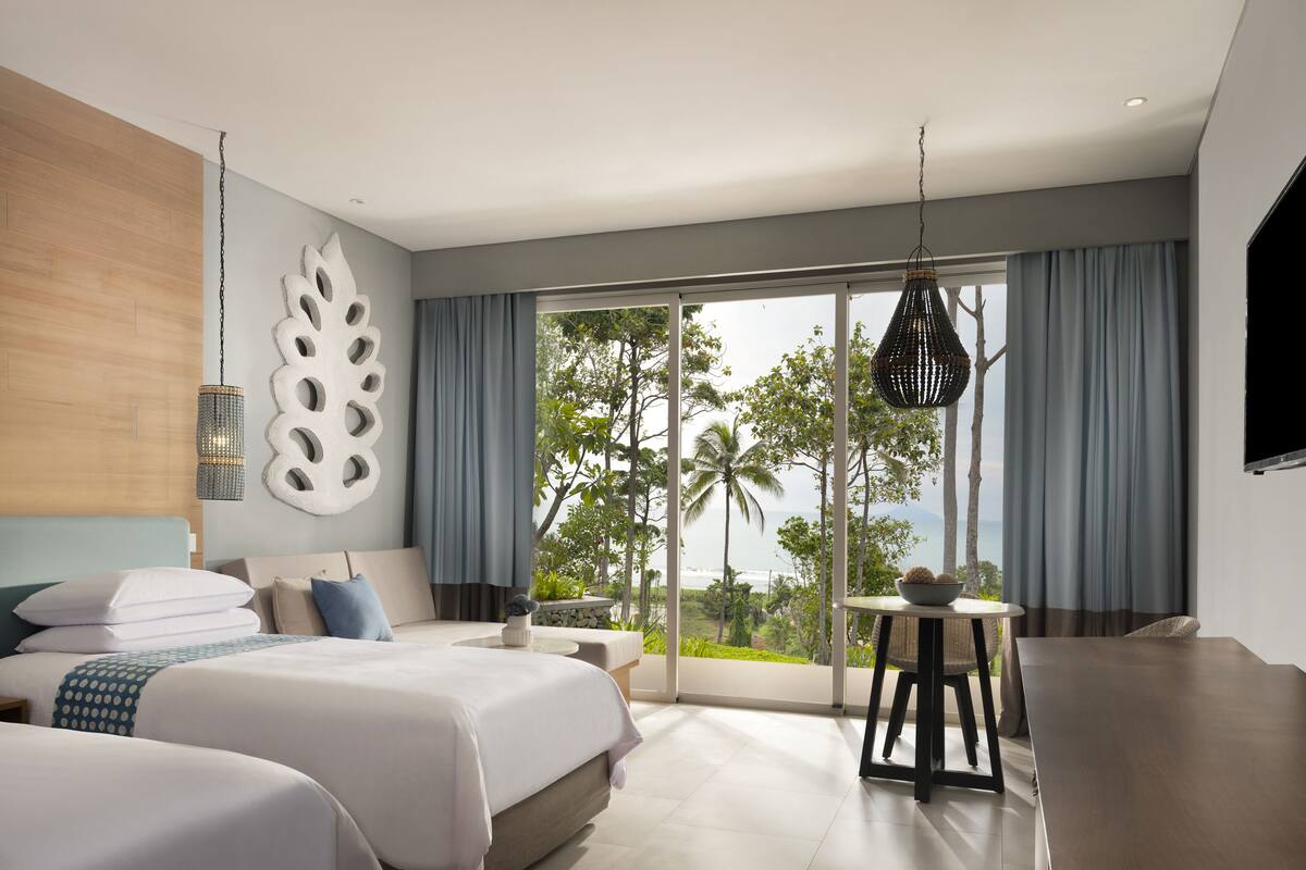 Habitación de hotel moderna con una cama grande, una mesita pequeña y vistas al exterior.
